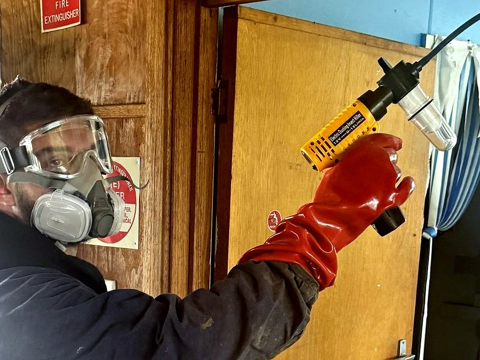 Zap It technician in a respirator, goggles and gloves treating a door frame